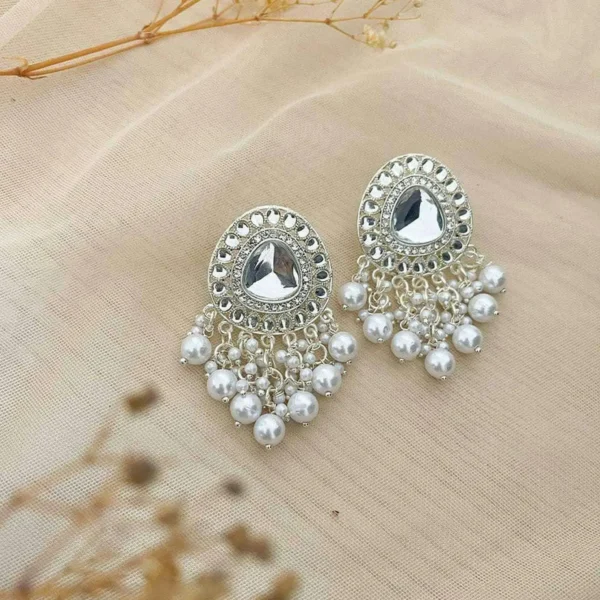 Beautiful silver earrings embellished with pearls on a soft fabric background.