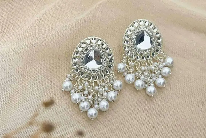 Beautiful silver earrings embellished with pearls on a soft fabric background.