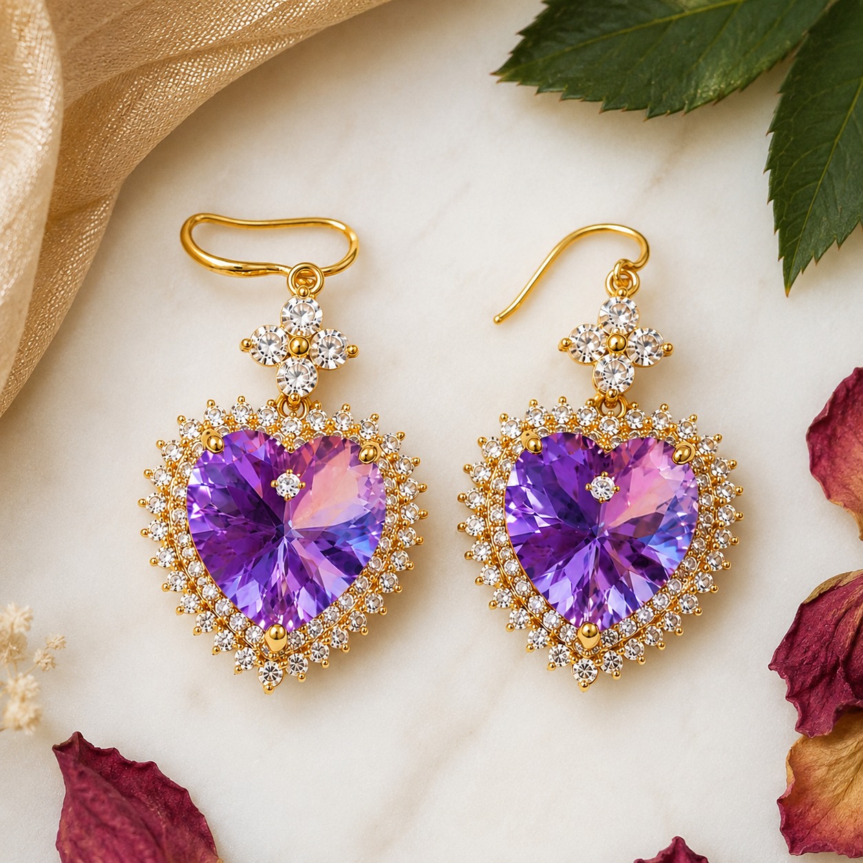 Flat lay styling of gold-plated purple heart drop earrings with a silk scarf and a small gift box — House of Ruhira