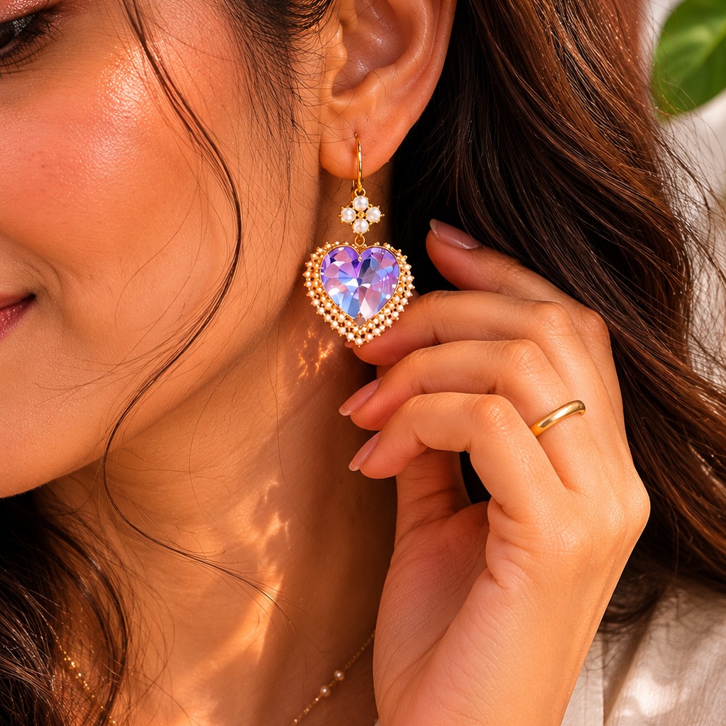 Model wearing gold-plated purple heart drop earrings with clear cubic zirconia, showcasing their elegant dangle — House of Ruhira