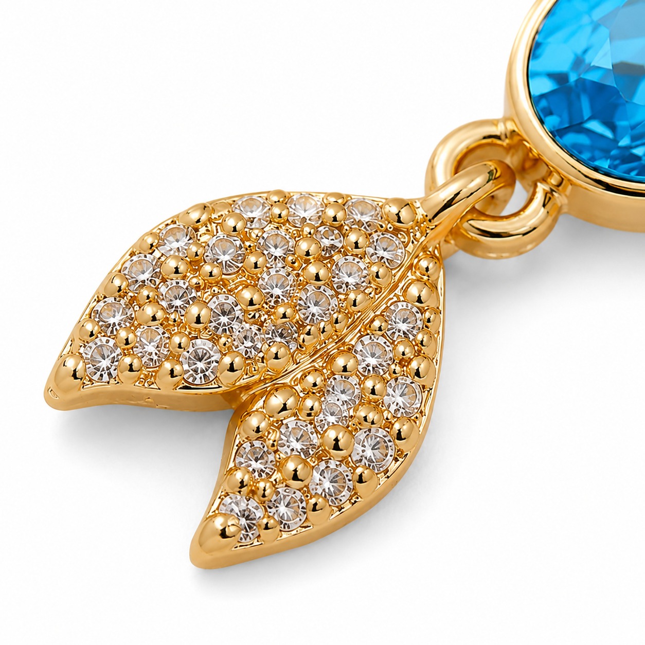 Extreme macro detail of the blue oval crystal and pave-set tail of the gold-toned drop earring — House of Ruhira
