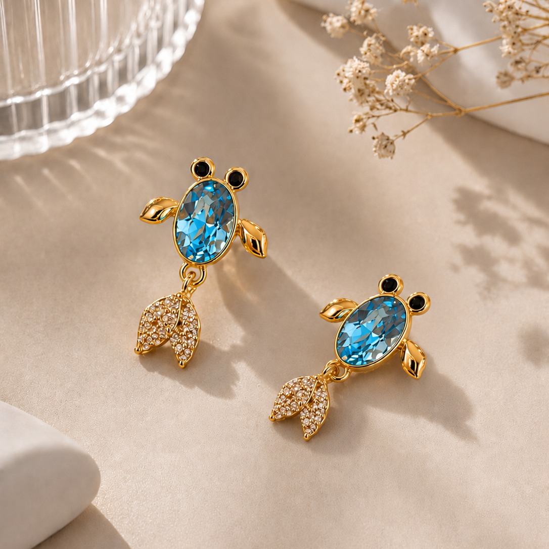 Pair of gold-toned blue crystal drop earrings with pave tails on a clean white studio background — House of Ruhira