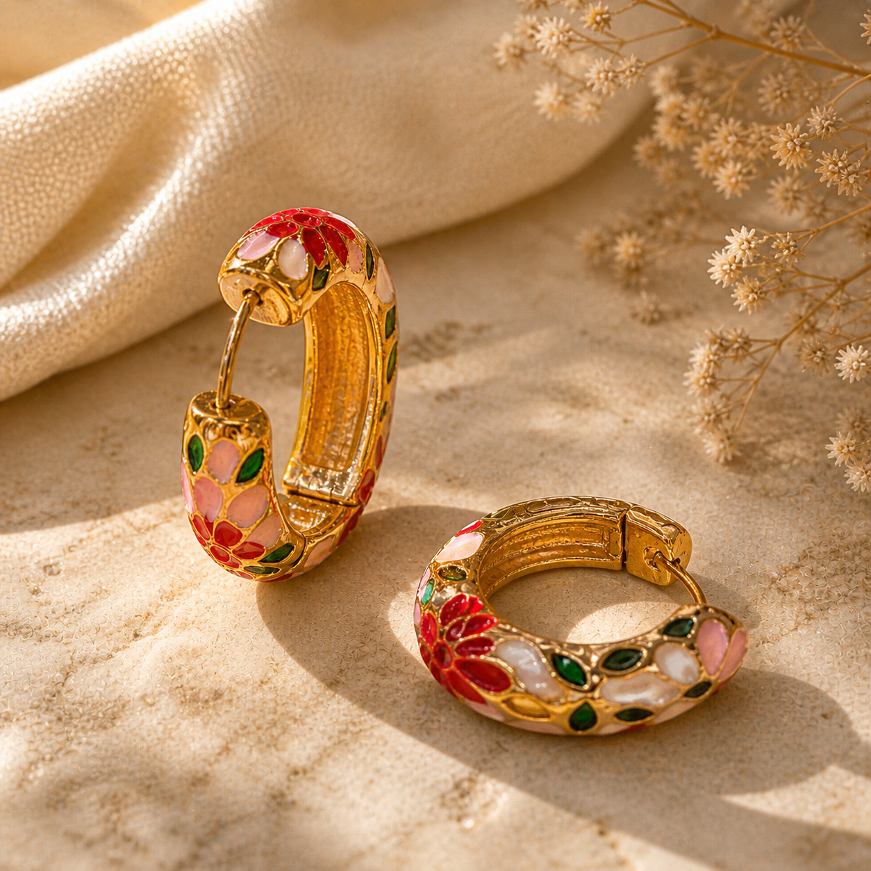 Flat lay styling of gold-plated enamel hoop earrings with floral enamel design, styled with a silk scarf and a small clutch bag — House of Ruhira