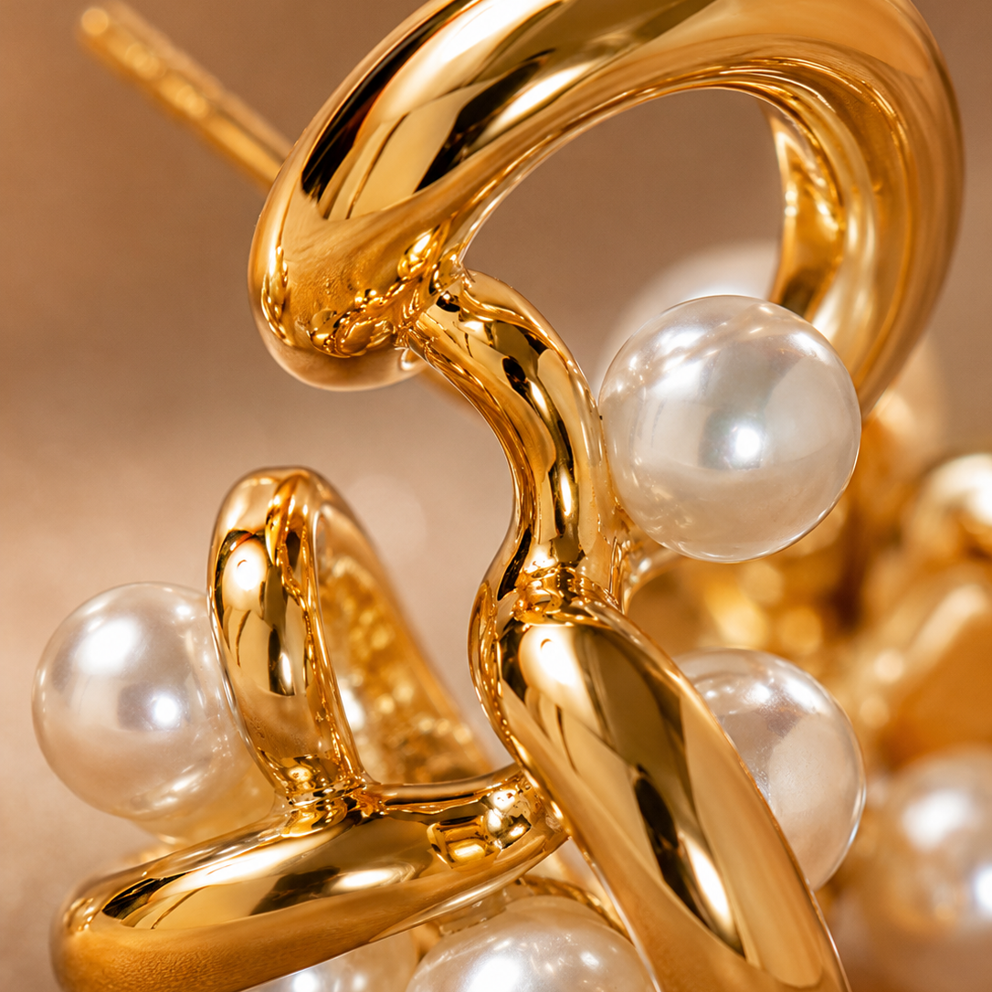 Extreme macro close-up of the intricate gold intertwine and smooth white imitation pearls on a modern drop earring — House of Ruhira