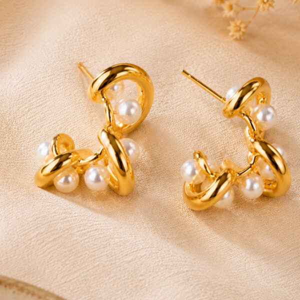 Two modern gold pearl drop earrings with intertwined design and lustrous imitation pearls on a clean white studio background — House of Ruhira
