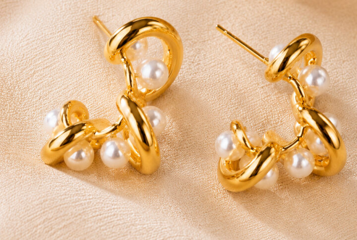 Two modern gold pearl drop earrings with intertwined design and lustrous imitation pearls on a clean white studio background — House of Ruhira