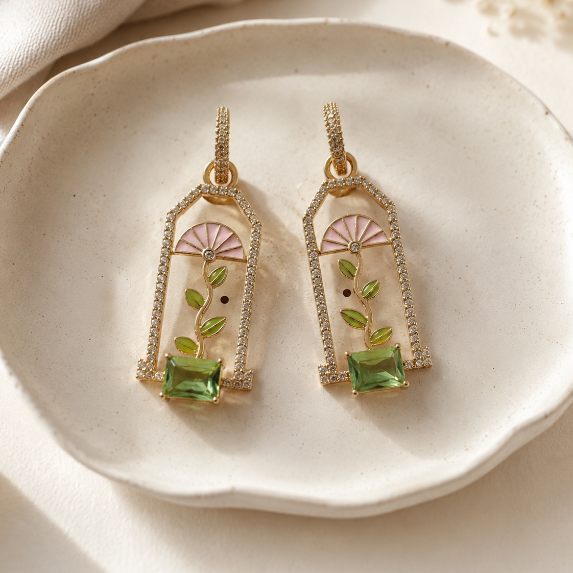 Flat lay styling of gold-plated enamel window garden drop earrings with complementary props — House of Ruhira