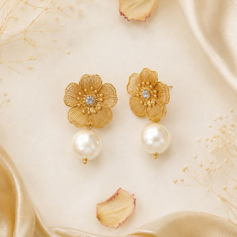 Flat lay styling of Golden Bloom Pearl Drop Earrings with elegant props like silk fabric and a small floral accent — House of Ruhira