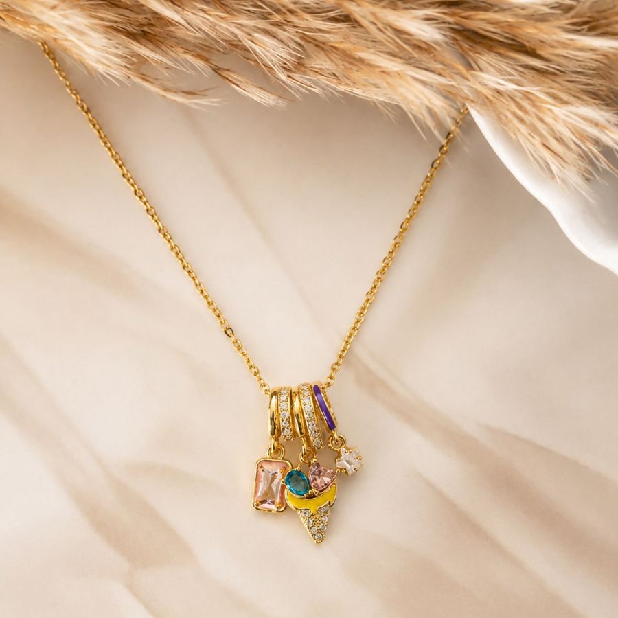 Flat lay styling of the Ruhira Whimsical Charm Necklace with complementary pastel accessories and a silk scarf – House of Ruhira