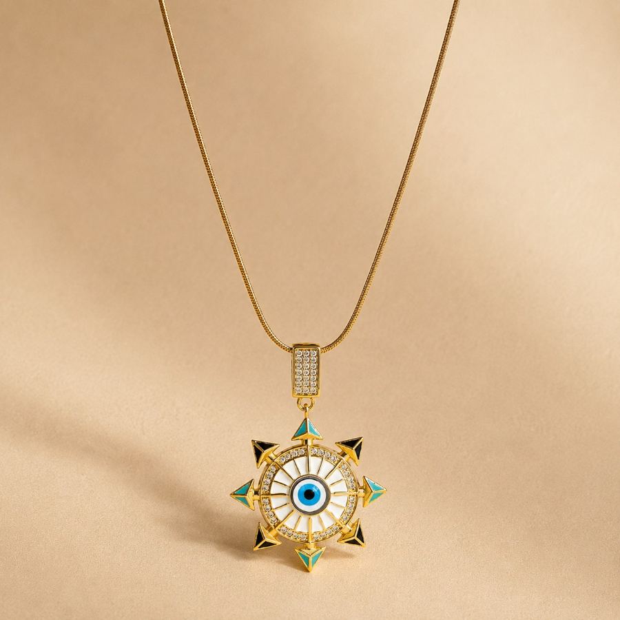 Flat lay styling of the gold evil eye pendant necklace with a silk scarf, a small notebook, and a delicate bracelet – House of Ruhira