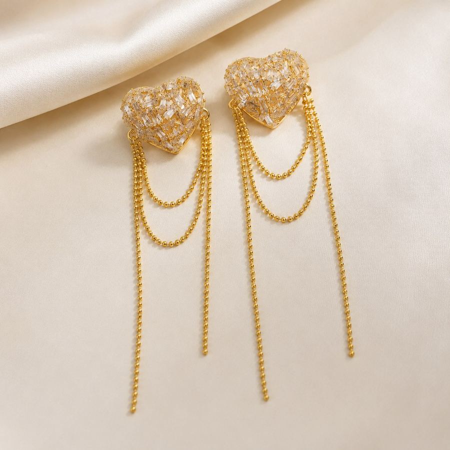 Flat lay styling of gold-toned heart-shaped crystal drop earrings with a silk scarf and a small clutch – House of Ruhira