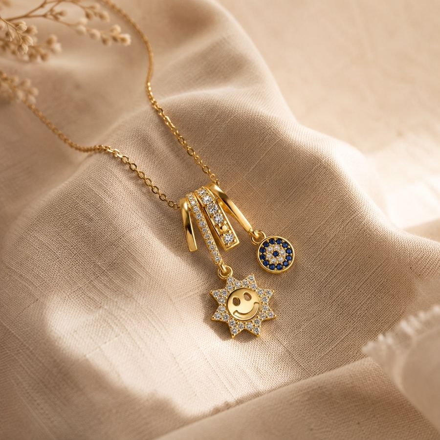 Extreme macro detail of the cubic zirconia studded sun charm and blue evil eye on a gold necklace – House of Ruhira