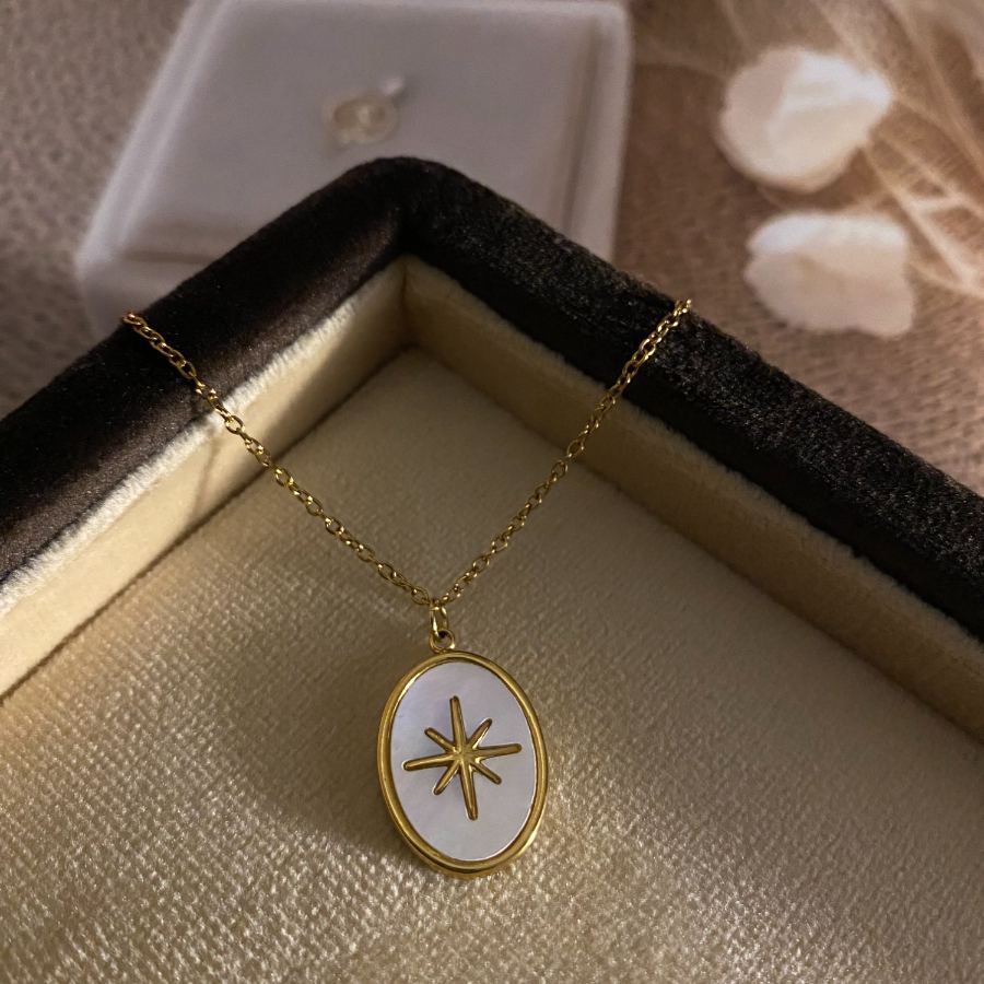Extreme macro detail of the gold starburst design on the white Mother-of-Pearl oval pendant of a necklace – House of Ruhira